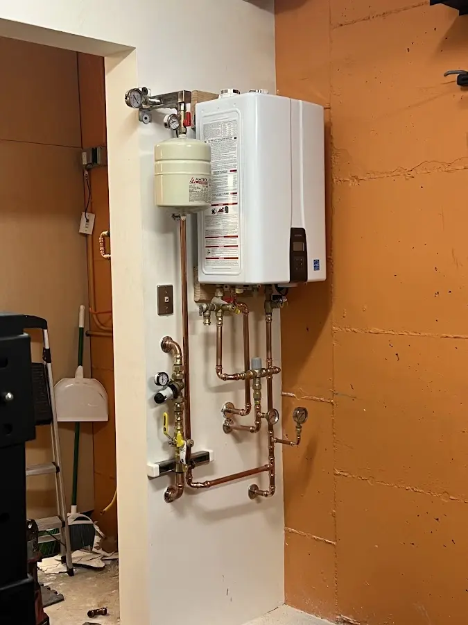 Plumbing technician inspecting water heater connections in Iowa Colony